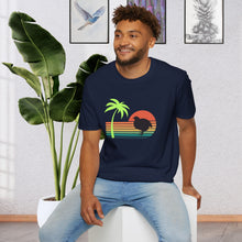 A man wearing a navy blue T-shirt that has a color line sunset ranging from orange at the top to teal at the bottom. There is a coturnix quail in the middle of the sun and there is a vibrant green palm tree .