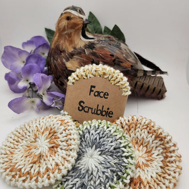 Pack of 3, 100% cotton face scrubbies in variegated colors sitting in front of a bird