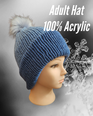 Beanie type hat in blue with a pompom on top displayed on a manakin with a snowflake background