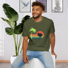 A man wearing a Military Green T-shirt that has a color line sunset ranging from orange at the top to teal at the bottom. There is a coturnix quail in the middle of the sun and there is a vibrant green palm tree .