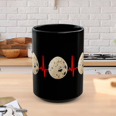 A black mug sitting on a kitchen counter featuring quail eggs around it with a red EKG line in the background! 