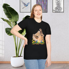 A girl wearing a  Black T-shirt. This is a unique and stylish piece of clothing that features a beautifully detailed illustration of a Coturnix Quail. The illustration is printed in a natural brown hue, giving the shirt a rustic and earthy feel with colorful flowers.
