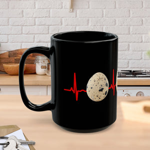 A black mug sitting on a kitchen counter featuring quail eggs around it with a red EKG line in the background!