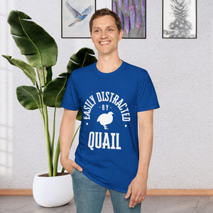 A man standing in front of a plant wearing a Royal Blue T-shirt that says Easily distracted by Quail in white lettering.  The shirt has a silhouette of a quail in the center.