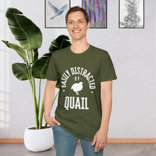 A man standing in front of a plant wearing a Military Green T-shirt that says Easily distracted by Quail in white lettering. The shirt has a silhouette of a quail in the center.