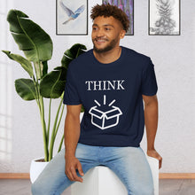a man sitting on a stool in front of a plant wearing a Navy Blue T-Shirt that says the Word Think in white ink above a picture of an open box which is also white.