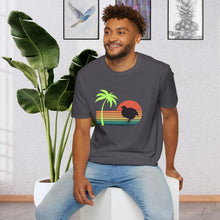A man wearing a charcoal grey T-shirt that has a color line sunset ranging from orange at the top to teal at the bottom. There is a coturnix quail in the middle of the sun and there is a vibrant green palm tree .