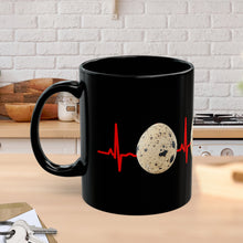 A black mug sitting on a kitchen counter featuring quail eggs around it with a red EKG line in the background!