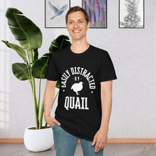 A man standing in front of a plant wearing a Black T-shirt that says Easily distracted by Quail in white lettering. The shirt has a silhouette of a quail in the center.