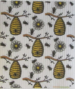 a Swedish dishcloth featuring honey bees, bee hives on branches and white flowers with a yellow center